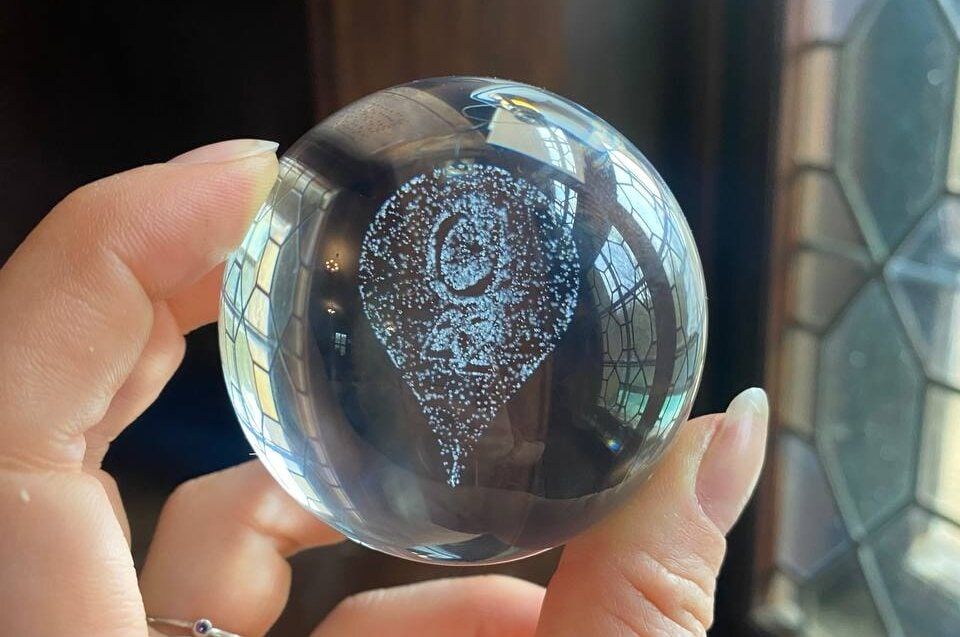 A hand holding a crystal orb with a part of the Q42 logo engraved inside