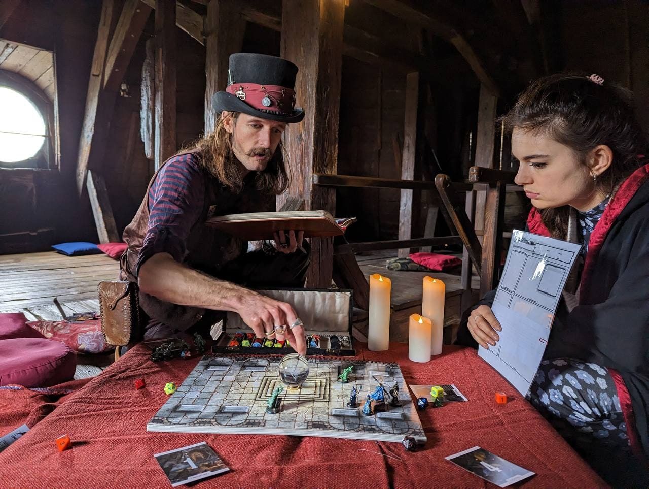 A game master in a top hat leads a Dungeons & Dragons quest by candlelight in the castle attic