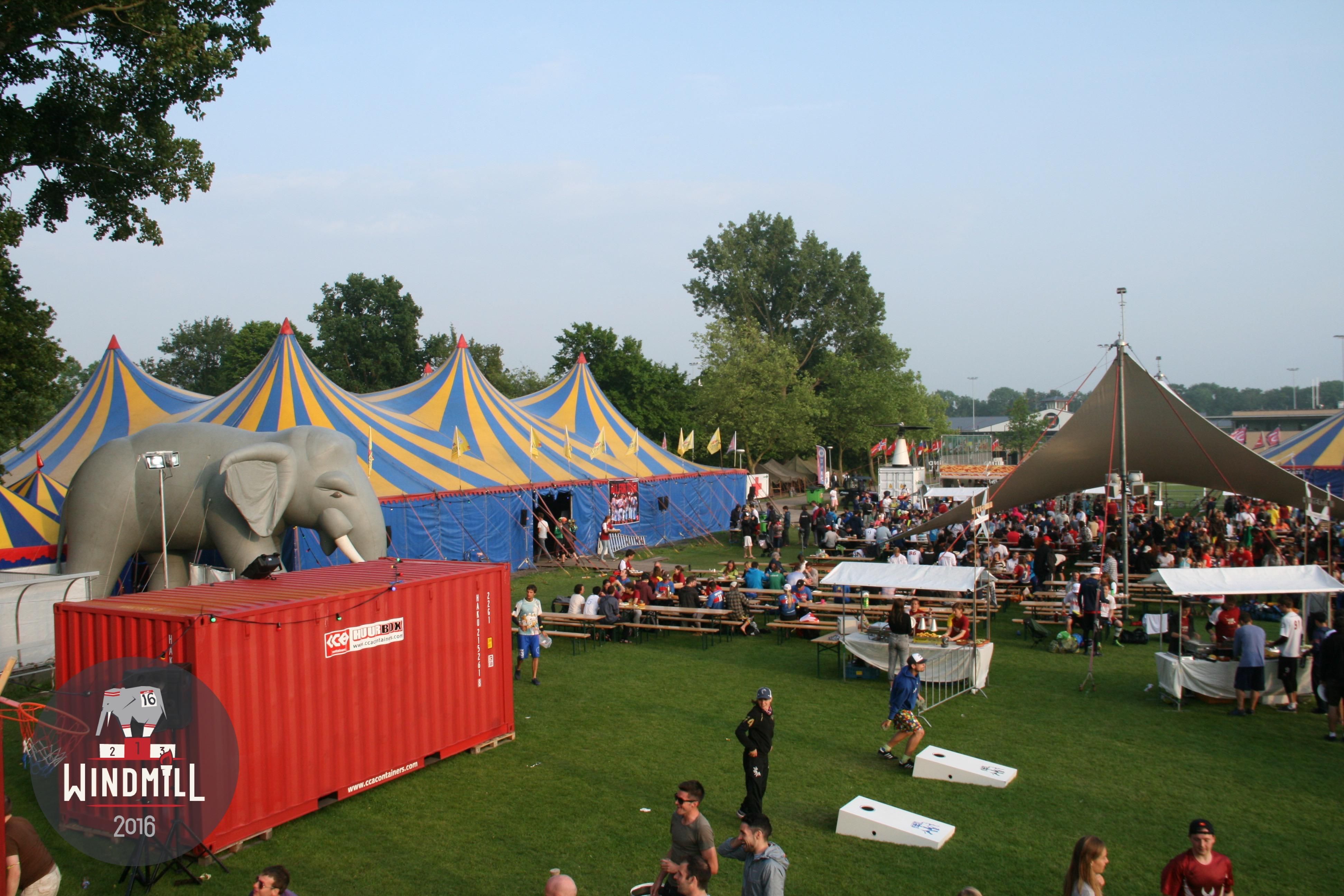 Blue and yellow circus tents, an inflatable elephant and a crowd on the grass at the Windmill tournament