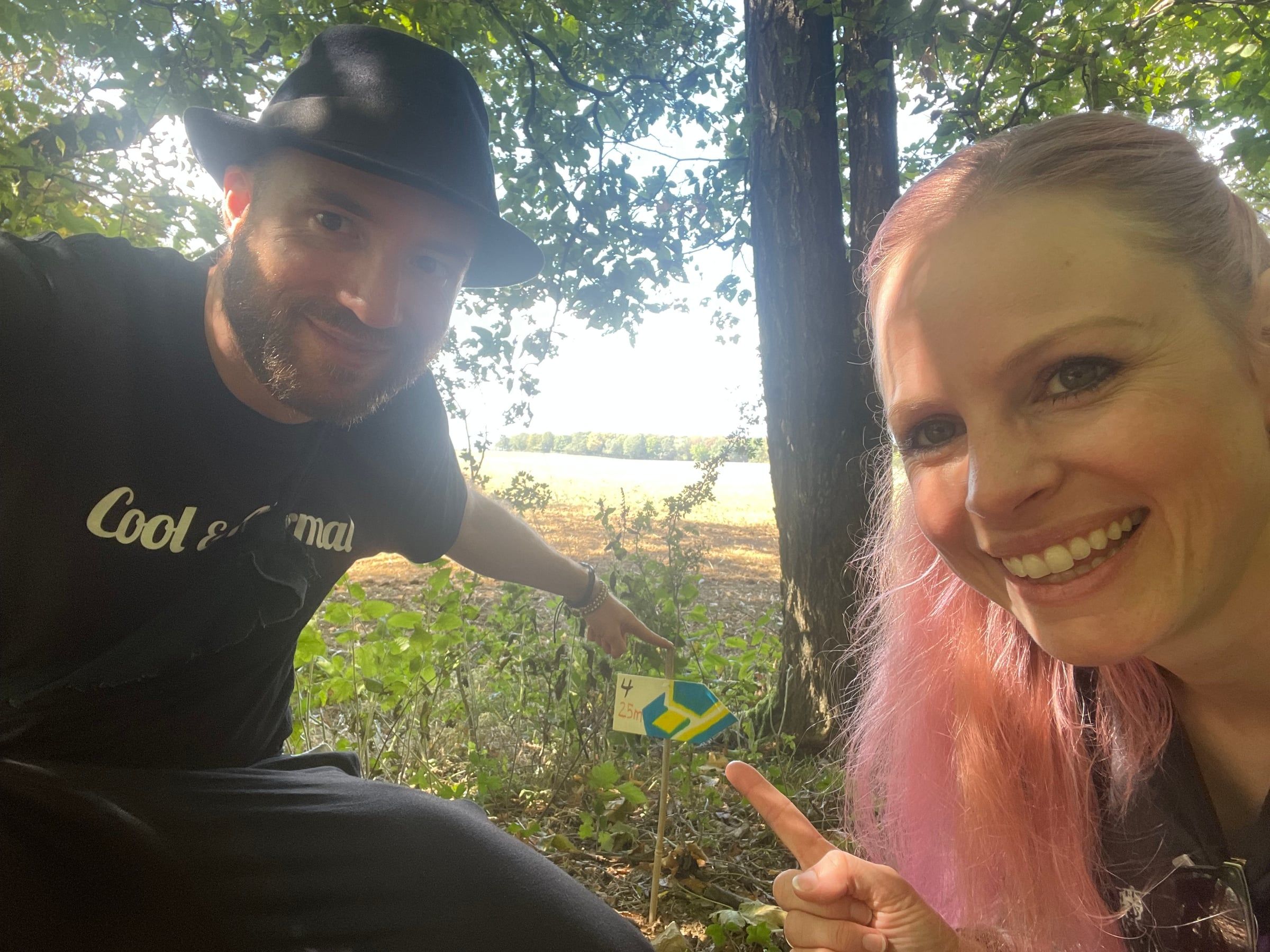 Thomas Lievestro and Camilla van Wirdum take a selfie in the forest, pointing at a colourfully decorated arrow sign